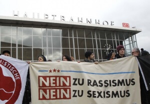 People protest  in front of the main  station in Cologne, Germany, on Wednesday, Jan. 6, 2016. The poster reads: "No to Racism, No to Sexism".  More women have come forward alleging they were sexually assaulted and robbed during New Years celebrations in the German city of Cologne, as police faced mounting criticism for their handling of the incident.  (AP Photo/Hermann J. Knippertz)